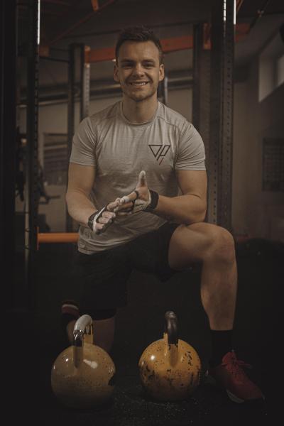 Oscar sidder på hug foran to kettlebells