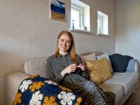 Amalie smiler og sidder med sit strikketøj