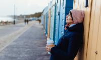 Billede af kvinde med kaffe ved strandpromenade