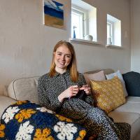 Amalie smiler og sidder med sit strikketøj