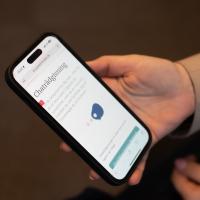 Chatrådgivning, billede, hånd holder telefon, hvor der ses hjemmesiden for chatrådgivning