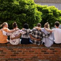 Gruppe af mennesker, sidder på mur, væg, arme, holder om hinanden