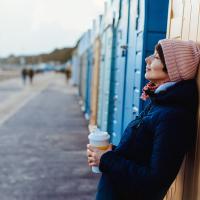 Billede af kvinde med kaffe ved strandpromenade
