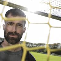 Portrætbillede af Martin Mikkelsen taget gennem et fodboldnet