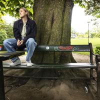 Kelly sidder på en bænkeryg med graffiti